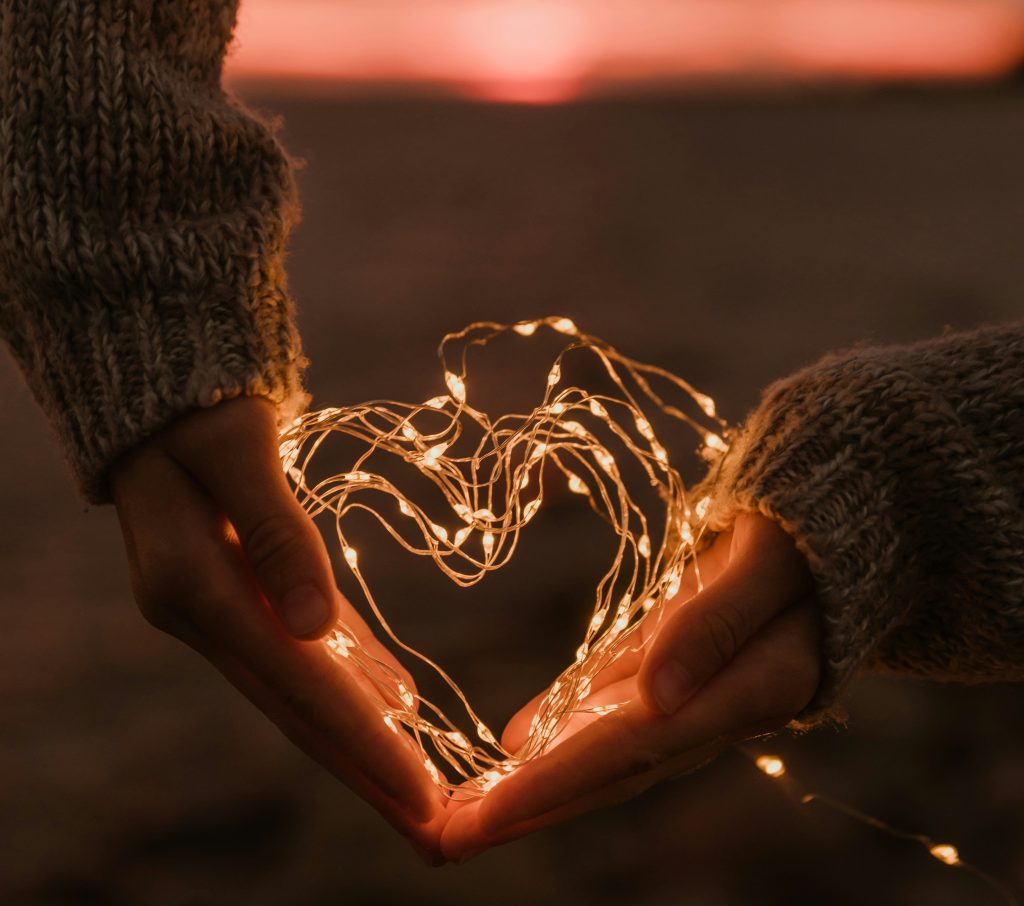 2 mains tenant une fine guirlande lumineuse en forme de coeur